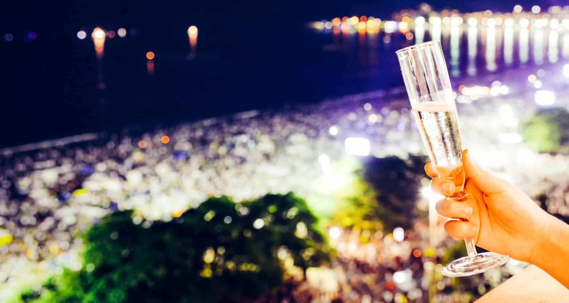 Hand holds out a champagne flute at night in Rio de Janeiro, Brazil