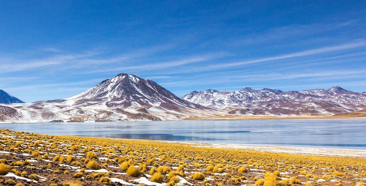 Snow-dusted volcanoes above a high-altitude lagoon in the Atacama Desert